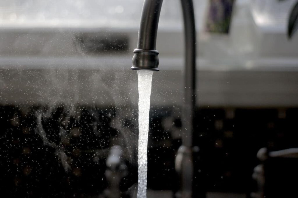 a stream of water infected with pfas drops from a black faucet