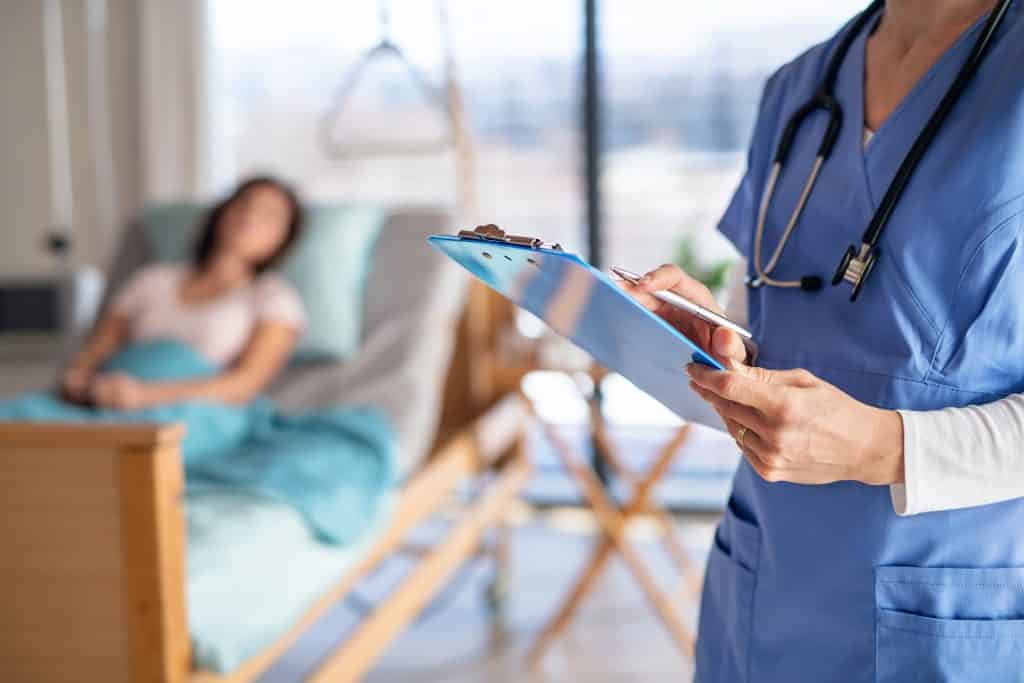 Nurse holding clipboard while talking to patient